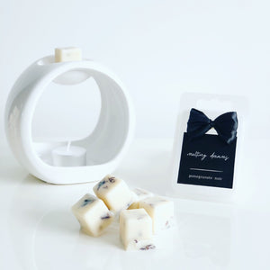 Luxury botanical pomegranate noir wax melts with a black label and white wax burner. 