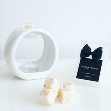 Load image into Gallery viewer, Luxury botanical unwind wax melts with a black label and white wax burner. 
